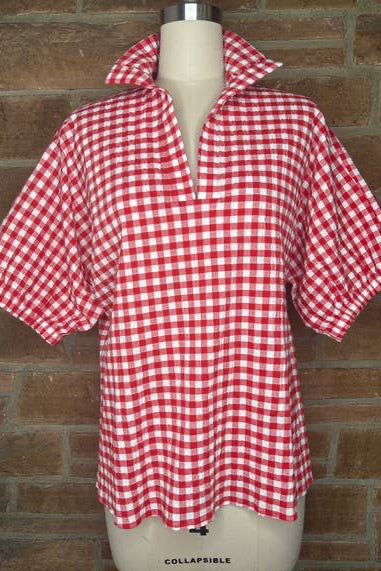 Red and white checkered shirt on a mannequin against a brick wall.